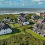 Cottage houses with thatched roofs along the coast with a view of the sea.
