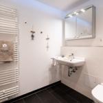Badezimmer mit Handtuchheizkörper, Waschbecken und Spiegelschrank.