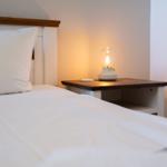 Ein Bett mit weißer Bettwäsche und einem Nachttisch mit einer Lampe.