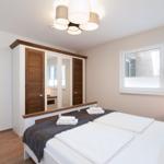 Schlafzimmer mit Doppelbett, Kleiderschrank und Fenster.