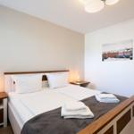 Schlafzimmer mit Bett, Nachttischen und Wandbild.