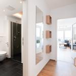 Flur mit Spiegeln und Holzregalen, Blick in Badezimmer und Wohnbereich.
