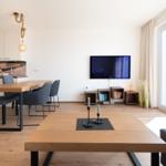 Wohn- und Essbereich mit TV, Esstisch und Holzboden.