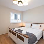 Schlafzimmer mit Bett, Nachttischen und Fenster.