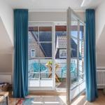 French doors with blue curtains lead to a terrace with table and chairs.