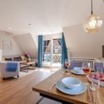 Dining area with table, chairs, and fruit. Living area with sofa, stairs, and window.