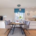 Dining area with table, chairs, and window. Kitchen with worktop and sink.