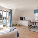 Living and dining area with balcony, TV, and wooden floor.