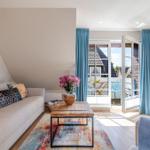 Living room with sofa, table, and view of balcony with chairs.