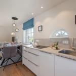 Kitchen with worktop, sink, and window. Dining area with table and chairs.