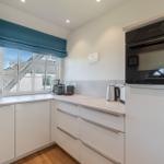 Kitchen with white cabinets, window, and built-in oven.