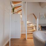 Living area with sofa, stairs, and coat rack