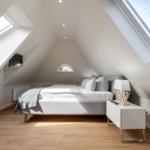 Attic room with sloped ceilings, bed, nightstand, and two skylights.