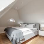 Bedroom with sloped ceiling, bed, nightstand, and window.
