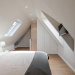 Bedroom with sloped ceiling, skylight, bed, wardrobe, and wall-mounted TV.