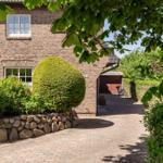 House with stone wall, manicured garden bed, and gravel path. Bicycles are in the back yard.