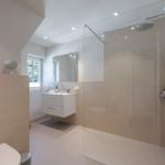 Bathroom with shower, sink and toilet. Window with view outside.