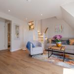 Living room with sofa, armchair, and table under sloped ceiling.