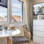 Tisch mit Frühstück und Sessel vor Fenster mit Blick auf Dächer.