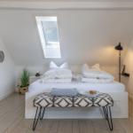 Schlafzimmer mit Dachschrägen, Dachfenster, Bett und Bank.
