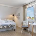 Schlafzimmer mit Dachfenster, Bett, Stuhl und Tisch mit Frühstück.