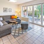 Wohnzimmer mit Sofa, Tisch und Terrassenzugang.