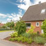 Ein Einfamilienhaus mit Ziegeldach, Vorgarten und gepflastertem Weg.