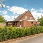 Ein zweistöckiges Haus aus rotem Backstein mit Dach und Garten.