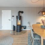 Ein Raum mit Esstisch, Kamin und Wandbild. Holzboden und moderne Möbel.