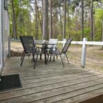 Terrasse mit Tisch und Stühlen im Wald. Holzdeck und weißer Zaun.