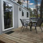 Terrasse mit Tisch und Stühlen vor einem Ferienhaus in einem Wald.