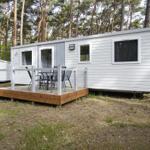Wohnwagen mit Terrasse und Sitzgelegenheiten im Wald