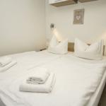 Schlafzimmer mit Doppelbett, weißen Bettwäsche und zwei Handtüchern.