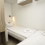 Zimmer mit einem Bett, weißen Bettwäsche und Handtüchern. Holzpaneel an der Wand.