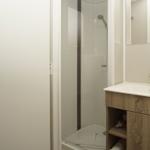 Badezimmer mit Dusche, Waschbecken und Spiegel.