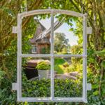 Through a window in the garden, a house with a thatched roof and terrace is visible.