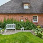 Red brick building with thatched roof, white bench, and green lawn area.