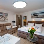 A bedroom with bed, sofa, and kitchen area. Wall paintings show beach scenes.