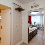 Apartment with bedroom, bathroom, and kitchen area. Doorway shows bedroom with bed.