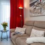 A living area with a brown sofa, red drapes, and wall decor.