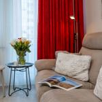 A sofa with cushions, a floor lamp, and a table with flowers and a cup.