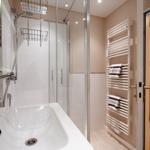 Bathroom with shower, sink, and towel warmer with towels.