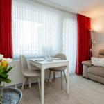Living room with sofa, dining table, red curtains, and flowers.