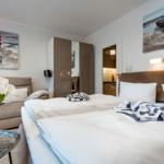 Bedroom with bed, sofa, wall art, and flowers on table.