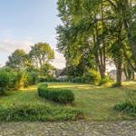 Green garden with trees and stone path in the foreground.
