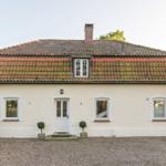 House with red tiled roof, white facade, and garden with plants.