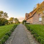 Haus mit Strohdach und gepflastertem Weg durch grünen Garten.