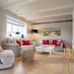 Wohnzimmer mit Sofa, Sessel, Couchtisch und Wandfliesen. Fenster mit Rollladen und Wanddekoration.