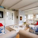Wohnzimmer mit Kamin, Sofa, Couchtisch und Fernseher. Blick in Esszimmer.
