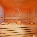 Sauna mit Holzbank, Eiche und Thermometer an der Wand.